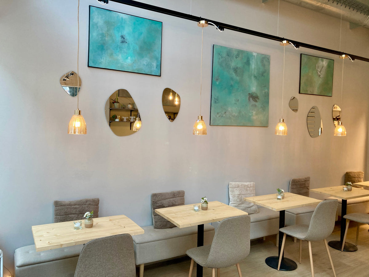 Ljus och modern restaurangmiljö med bord, lampor och konst hos Hey Lucie i Uppsala